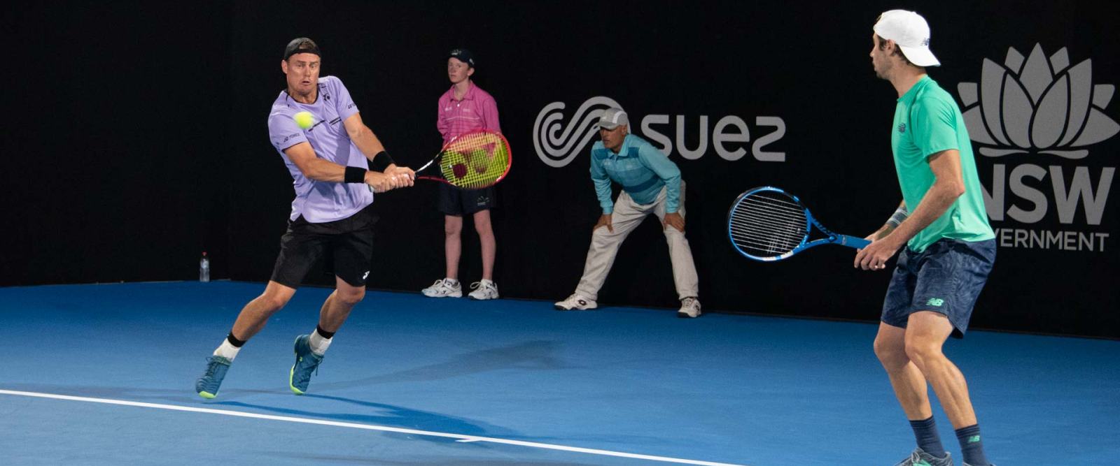 Players in a rally on a blue hard court at an Australian ATP tournament